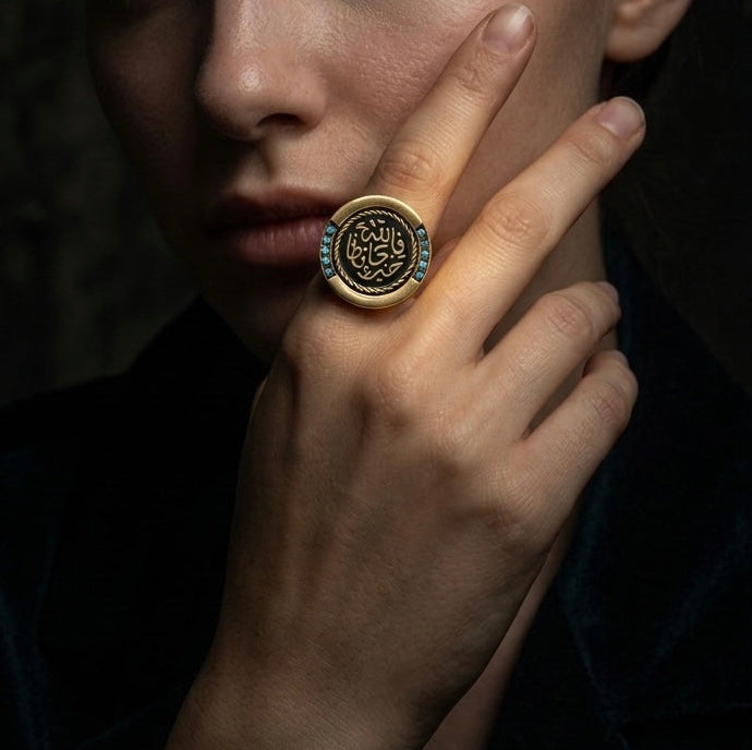 خاتم حماية ذهبي اللون مكتوب عليه "ما شاء الله" مرصع بالفيروز